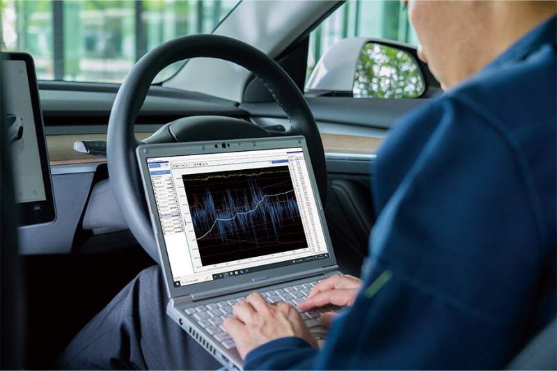Engineer reviewing real-time test data on in-vehicle laptop screen